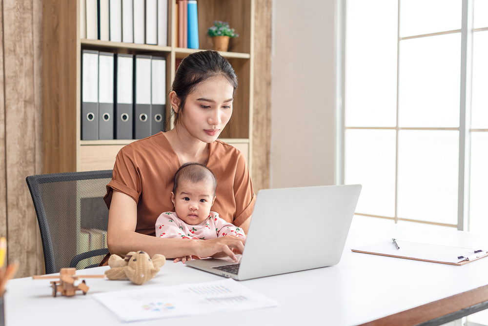 Image of a woman working at home with a baby sitting in her lap